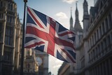 Fototapeta Londyn - A British Union Jack flag flies and flutters from a pole with London buildings in the background. Natural daylight. Generative AI.