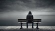 © ibreakstock - Anxiety and depression lonely solitary man in hoodie sitting on bench against empty dark grey background with copy space