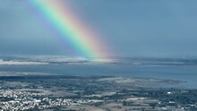 Montpellier's picturesque aerial vista includes vineyards, glimpses of the Mediterranean, and dancing rainbows amid clouds

