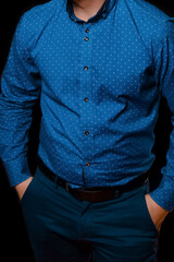 Men's business look and fashion style blue shirt with abstract pattern in small white polka dots posing with hands in pocket on dark background