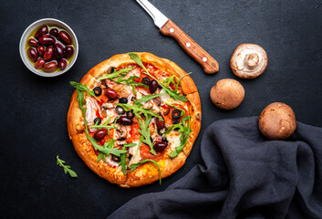 Wall Mural - Homemade Pizza with salami sausage, cheese, mushrooms, black olives, tomato sauce and arugula, black table background, top view