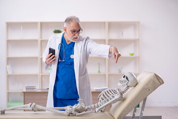 Wall Mural - Old male doctor and skeleton patient in the clinic