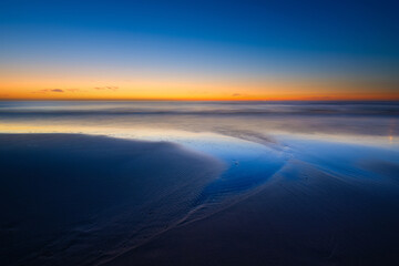 Wall Mural - a seascape during sunset. sand on the seashore. bright sky during sunset. a sandy beach at low tide.