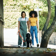 © aLListar/peopleimages.com - Love, holding hands and lesbian couple walking with dog in city street for exercise, bonding and fun. Lgbtq, animal and interracial young gay women in town road with pet puppy for fresh air together.