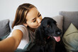 Kiss, selfie and woman with dog on home sofa to relax, love and play with animal. Pet owner, care and influencer person with companion, trust and friendship or social media profile picture and memory