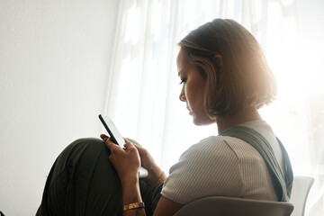 Poster - Phone, relax and young Asian woman in the living room sitting on a comfortable chair on a weekend. Calm, peaceful and female person networking on social media, mobile app or internet at apartment.