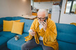 © Miljan Živković - one senior man sit on sofa bed hold thermometer check body temperature