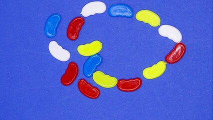 Wall Mural - Toy colorful plastic beans on blue background. Stop motion technique. 4k video capture