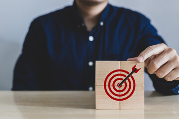 Wall Mural - A man putting wooden blocks with target icon which is the last piece. Concept of business success growth increase up in next year