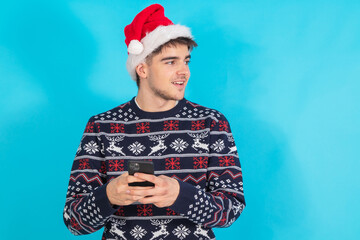 Wall Mural - young man with santa claus hat and mobile phone