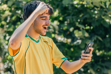 Wall Mural - smiling young man watching the game or video on the mobile phone, sport