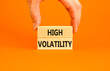 Leinwandbild Motiv High volatility symbol. Concept words High volatility on beautiful wooden blocks. Beautiful orange table orange background. Businessman hand. Business high volatility concept. Copy space.