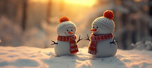 Snowmen Knitted With Red Wool Hat And Orange Scarf In Snow With Forest In Background.