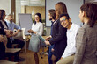 © Studio Romantic - Team of happy diverse multiracial people having fun at work after business training or corporate meeting, standing in office presentation room, talking and sharing their impressions