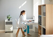 © Studio Romantic - Side view portrait of a young confident female doctor therapist in white medical uniform sitting at the desk on her workplace in medical office in clinic and working on a laptop computer.