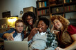 © Geber86 - Young and diverse group of friends watching a movie on laptop in the living room on the couch