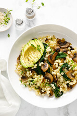 Wall Mural - Couscous with avocado, spinach and sauteed champignon mushrooms with onion, top down view