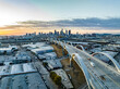 Aerial panoramic view of industrial urban borough and modern road bridge. Skyline with downtown skyscrapers against sunset sky. Los Angeles, California, USA