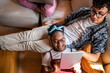 © Marko Geber - Young and diverse group of friends using a tablet on the couch at home