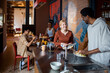 © Marko Geber - Young and diverse group of friends washing dishes after breakfast in their flatshare apartment