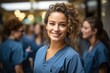 © Dionisio - young nurse smiling at camera, with her colleagues in the background