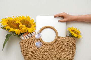 Sticker - Female hand with modern laptop, magazine and beautiful sunflowers in wicker bag on light background