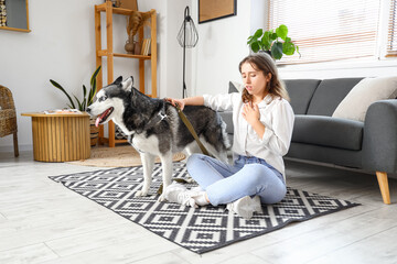 Wall Mural - Depressed young woman with husky dog at home