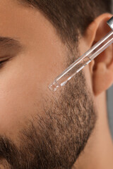 Poster - Man applying cosmetic serum onto face, closeup