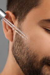 Poster - Man applying cosmetic serum onto face, closeup