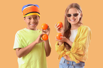 Wall Mural - Little children with fresh tangerines on orange background