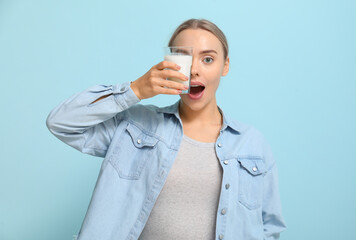 Wall Mural - Pretty young woman with glass of milk on blue background