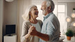 © Sasint - Keep moving. Romantic senior family couple wife and husband dancing to music together in living room, smiling laughing retired man and woman having fun, enjoying free time together at home