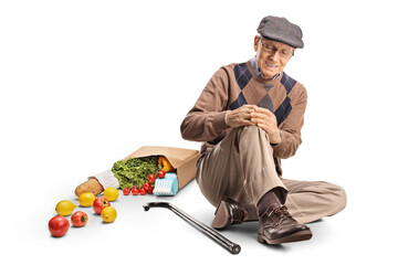 Poster - Senior man with a grocery bag sitting on the floor and holding his painful knee