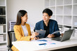 © Nuttapong punna - Two  Asian business  man and woman workers talking on the smartphone and using laptop Professionals in Teamwork  Finance, Marketing, and Success