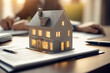 © Shubby Studio - a concept 3d render model of a small living house on a table in a real estate agency. estate agent and the buyer clients signing mortgage contract document on the blurry background. Generative AI