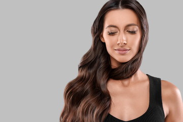 Wall Mural - Hair styling. Beautiful woman with wavy long hair on grey background, space for text