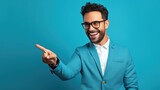 Fototapeta  - a man with black frame glasses wearing blue color office suit pointing his right index finger in front of blue background, smiling at pointed object