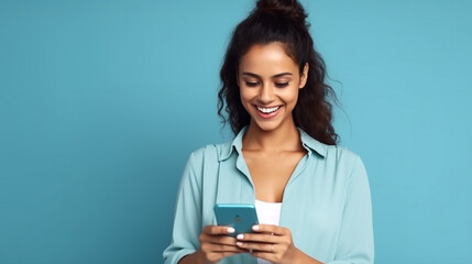 Young adult smiling happy pretty latin woman holding mobile phone looking at smartphone, typing message doing ecommerce shopping on cell, using trendy apps on cellphone isolated on blue background 