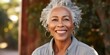 Smiley middle-aged woman with a short gray hair looking at camera. Close-up outdoor portrait of an elegant beautiful African American woman in her 50s.