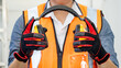 © Summer Paradive - Male worker with reflective orange vest and protective hand gloves pulling yellow safety ear muffs or ear protectors preparing to wear on his head. Equipment for high noise reduction