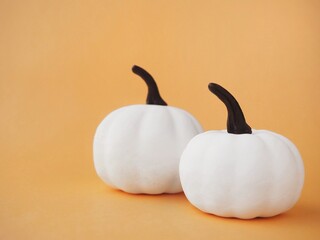 Orange background with two White pumpkins and copy space