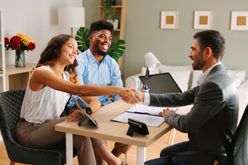 Wall Mural - Young Latin American couple makes a deal with an agent in the office and does handshake