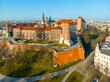 Krakow. Poland.  Wawel castle and cathedral with towers and Sigismund chapel with golden dome. Sandomierska and Senatorska towers. Promenades and walking people. Aerial view in sunset light in winter