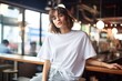 © Chanakan - young woman in a white T-shirt and shorts sits in a cafe.
