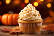Delicious pumpkin cupcake with buttercream on autumnal background.