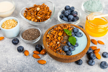 Bowl of granola with yogurt and fresh berries on a texture table. Yogurt berries, acai bowl, spirulina bowl. Healthy food, balanced breakfast. Strawberries, blueberries, kiwi, peach, almonds and chia.