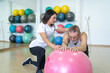 © ADDICTIVE STOCK - Focused woman helping man to do exercise on fitness ball