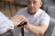 © fizkes - Caring nurse hold hands support comfort sick disabled senior 80s male patient with walking stick, caregiver or doctor help stand up ill old man with cane, rehabilitation, elderly healthcare concept