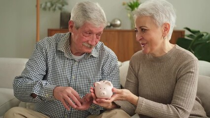 Wall Mural - Saving money investment for future. Senior adult mature couple holding piggy bank putting money coin. Old man woman counting saving money planning retirement budget. Saving investment banking concept