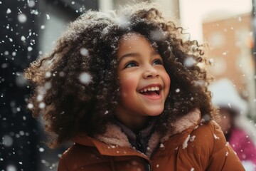 Happy black girl laughing at Christmas under the snow in winter